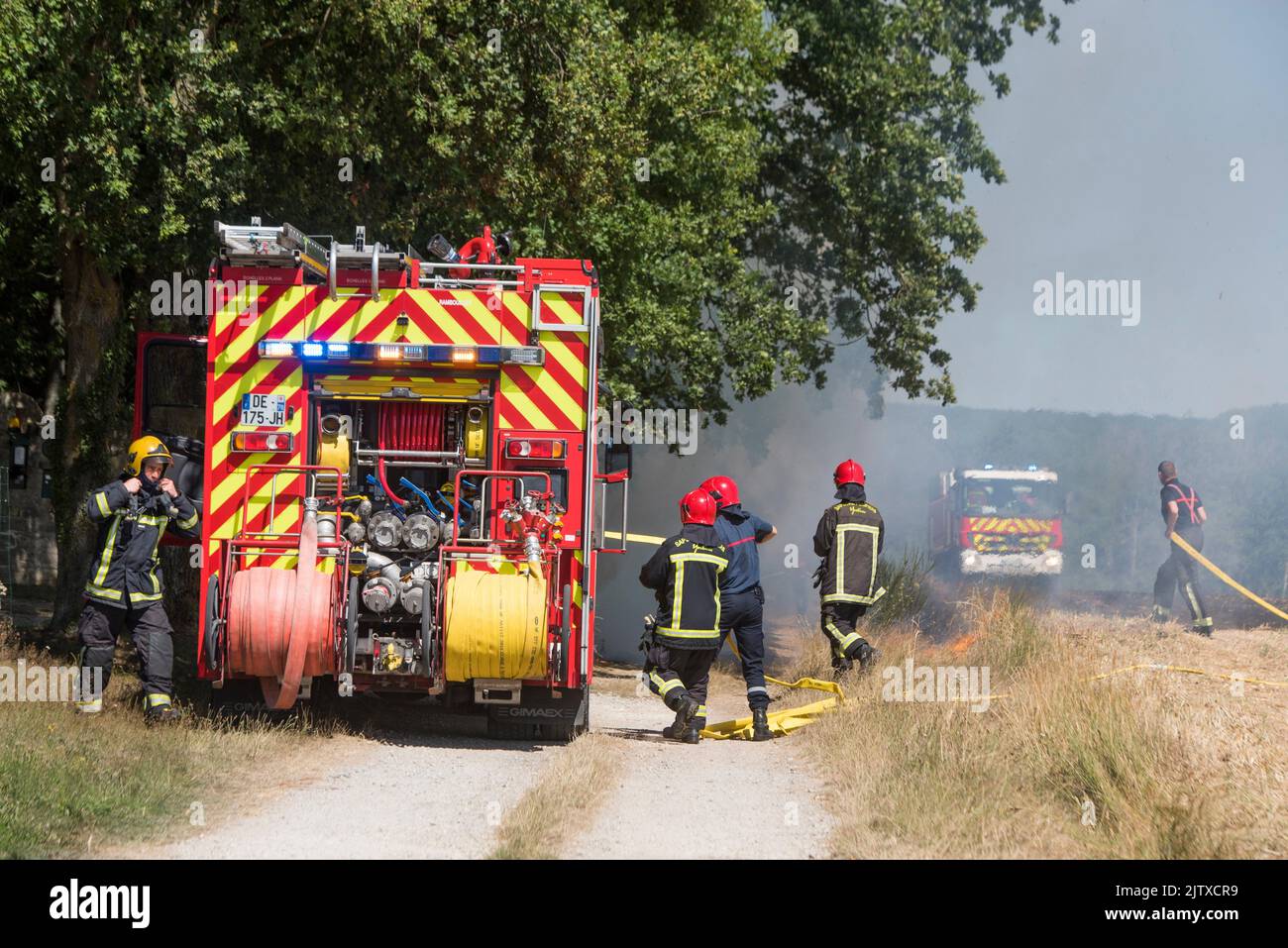 Firefighters extinguishing a stubble fire in a field already harvested, Eure-et-Loir department, Centre-Val-de-Loire region, France, Europe. Stock Photo