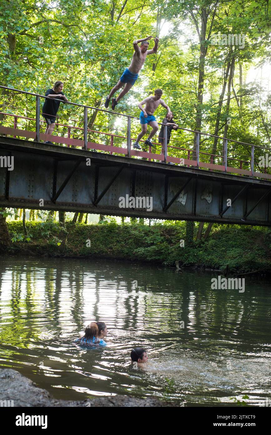 Young people jumping off a bridge in the Eure River, Eure-et-Loir department, Centre-Val-de-Loire region, France, Europe. Stock Photo