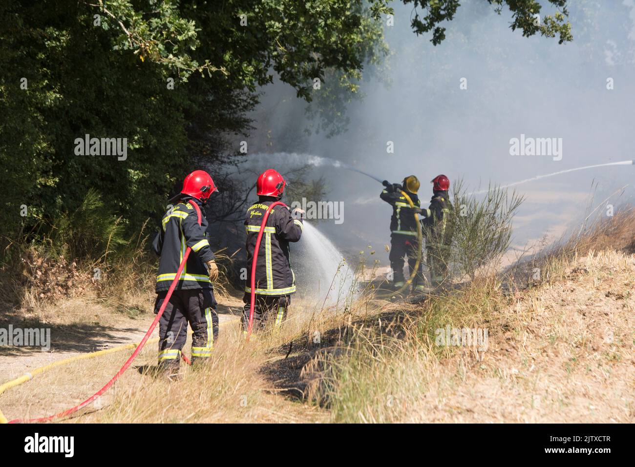 Firefighters extinguishing a stubble fire in a field already harvested, Eure-et-Loir department, Centre-Val-de-Loire region, France, Europe. Stock Photo
