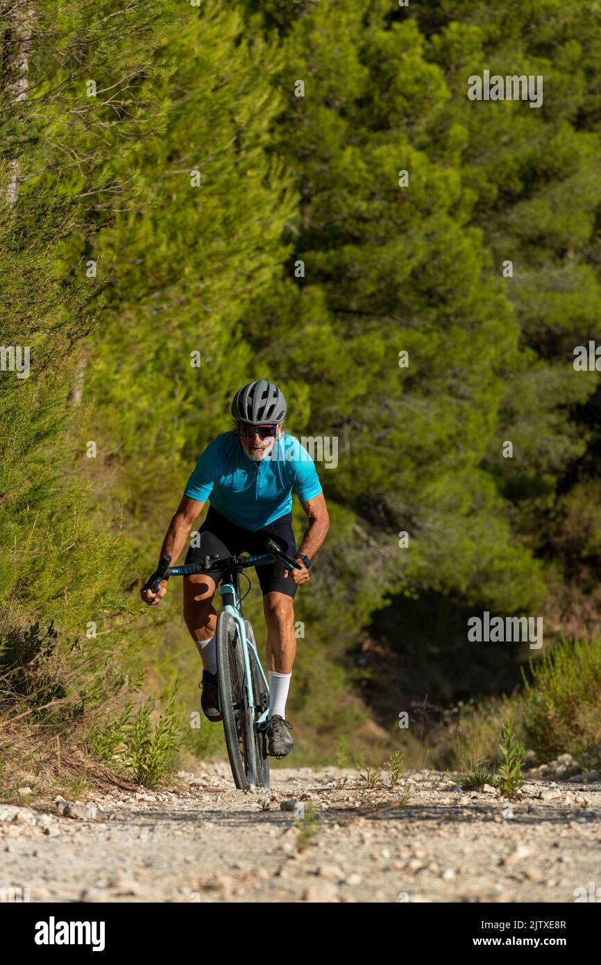A male cyclist in a gravel road bicycle ride in the  mountains of Costa Blanca, Alicante, Spain Stock Photo