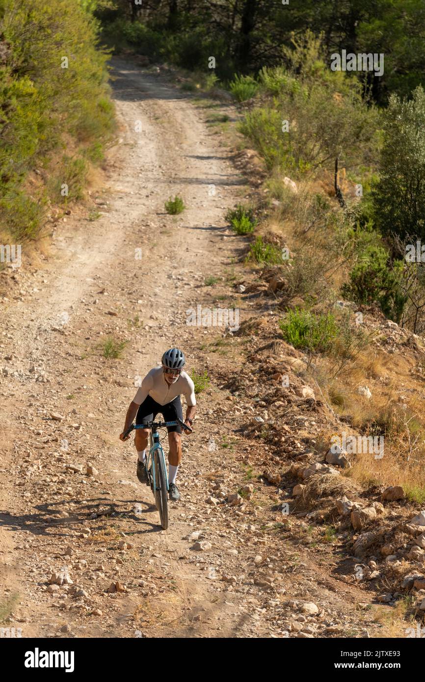 A male cyclist in a gravel road bicycle ride in the  mountains of Costa Blanca, Alicante, Spain Stock Photo