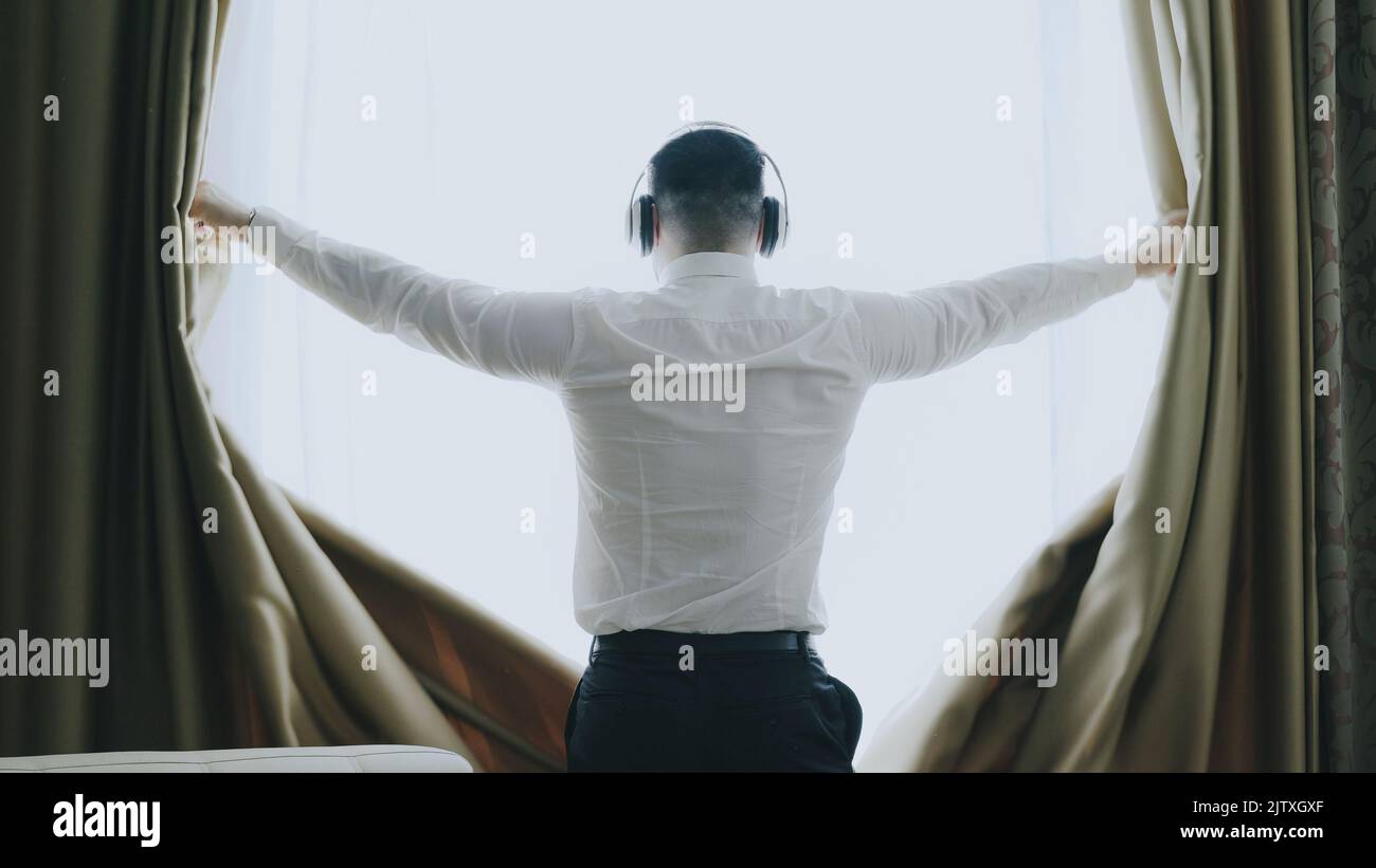 Silhouette man opening curtains looking hires