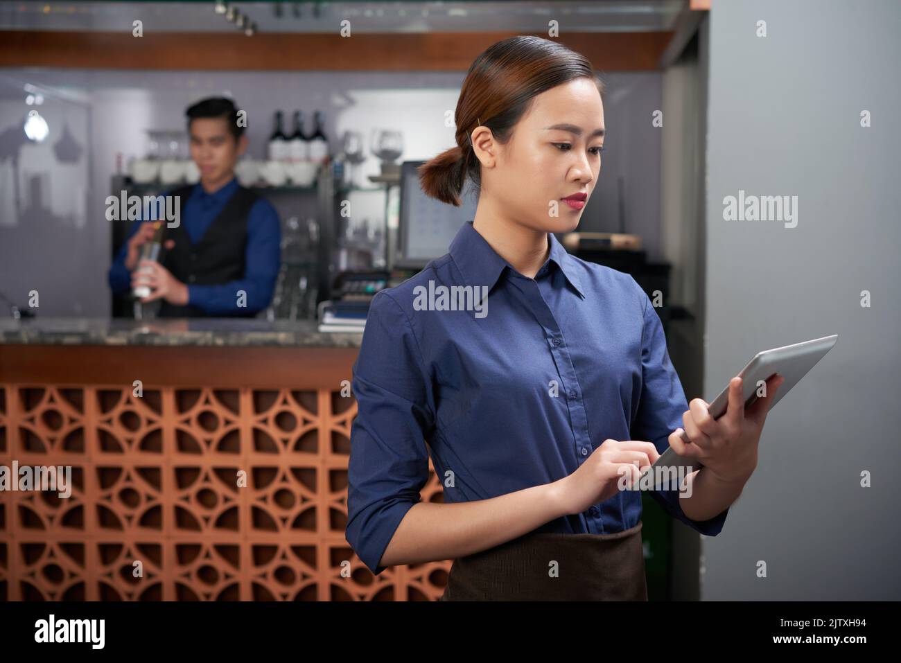 Young Vietnamese restaurant manager checking information in digital tablet Stock Photo