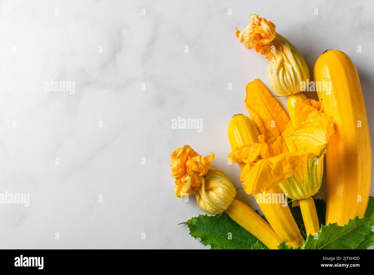 Fresh yellow zucchini or squash with flowers on white background. Top view with copy space. Fresh harvested vegetables Stock Photo