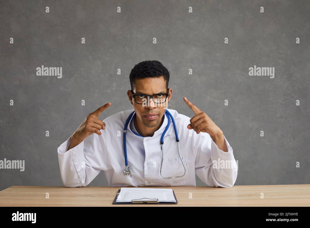 Angry American American man shows himself hinting that he is experiencing headaches and fatigue. Stock Photo