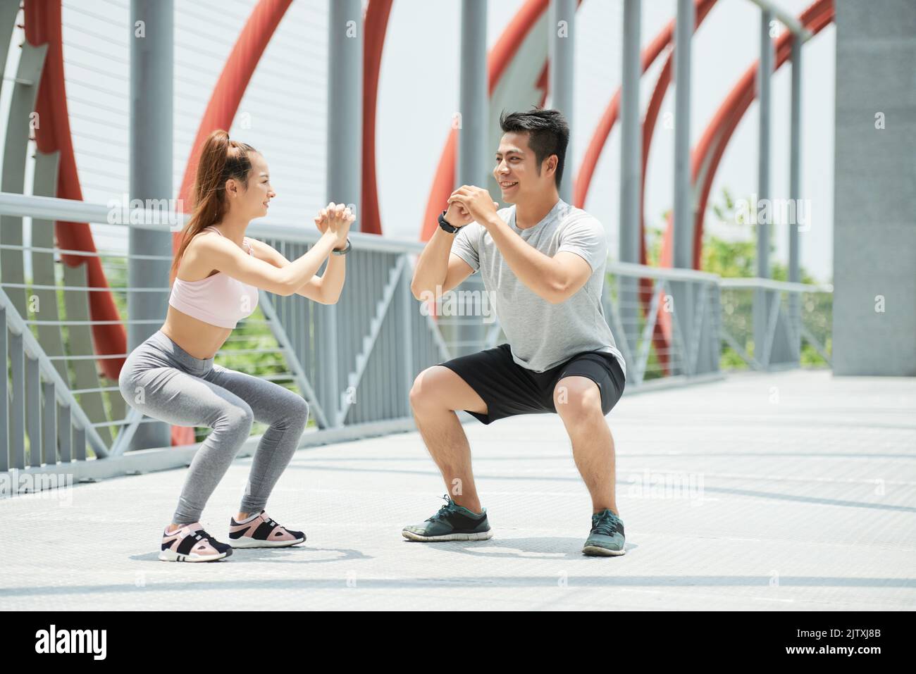 Happy young Vietnamese couple doing squats together Stock Photo