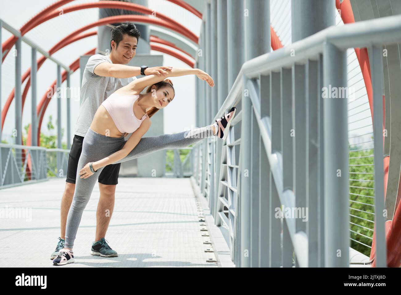 Vietnamese young man helping his girlfriend with stretching Stock Photo