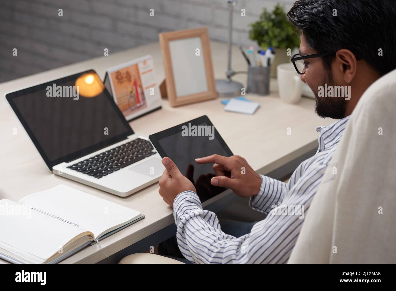 Businessman sitting at table and using application on digital tablet Stock Photo