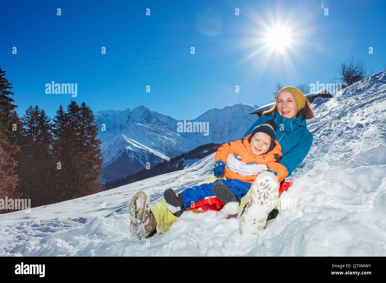 Mother go downhill together with little boy siting in the sledge Stock Photo