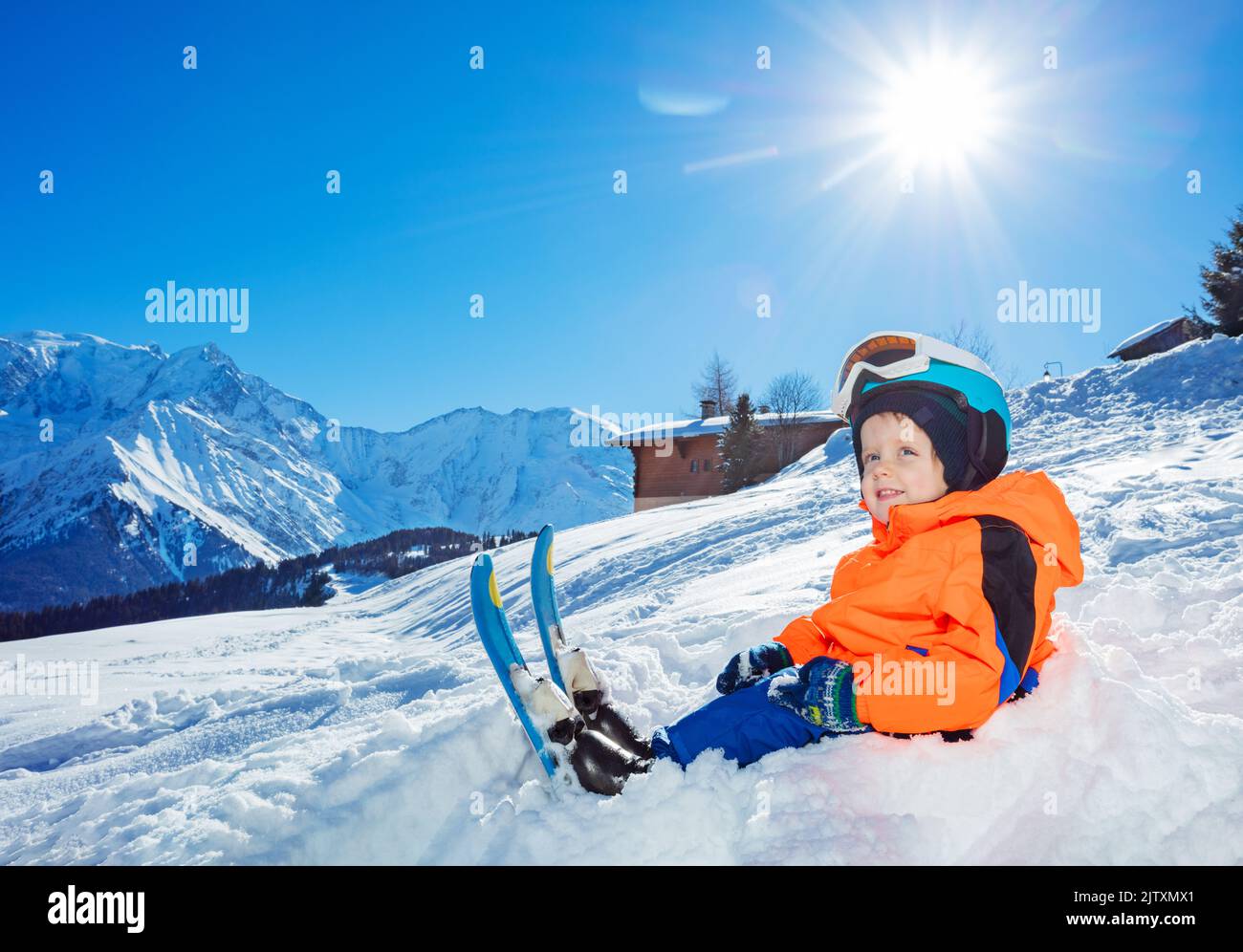 Smiling Boy with ski ready for skiing school sit in snow Stock Photo