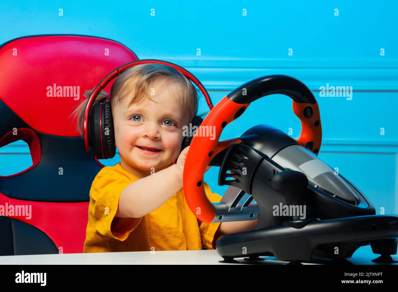 Little girl in headphones with steering wheel play race game Stock Photo