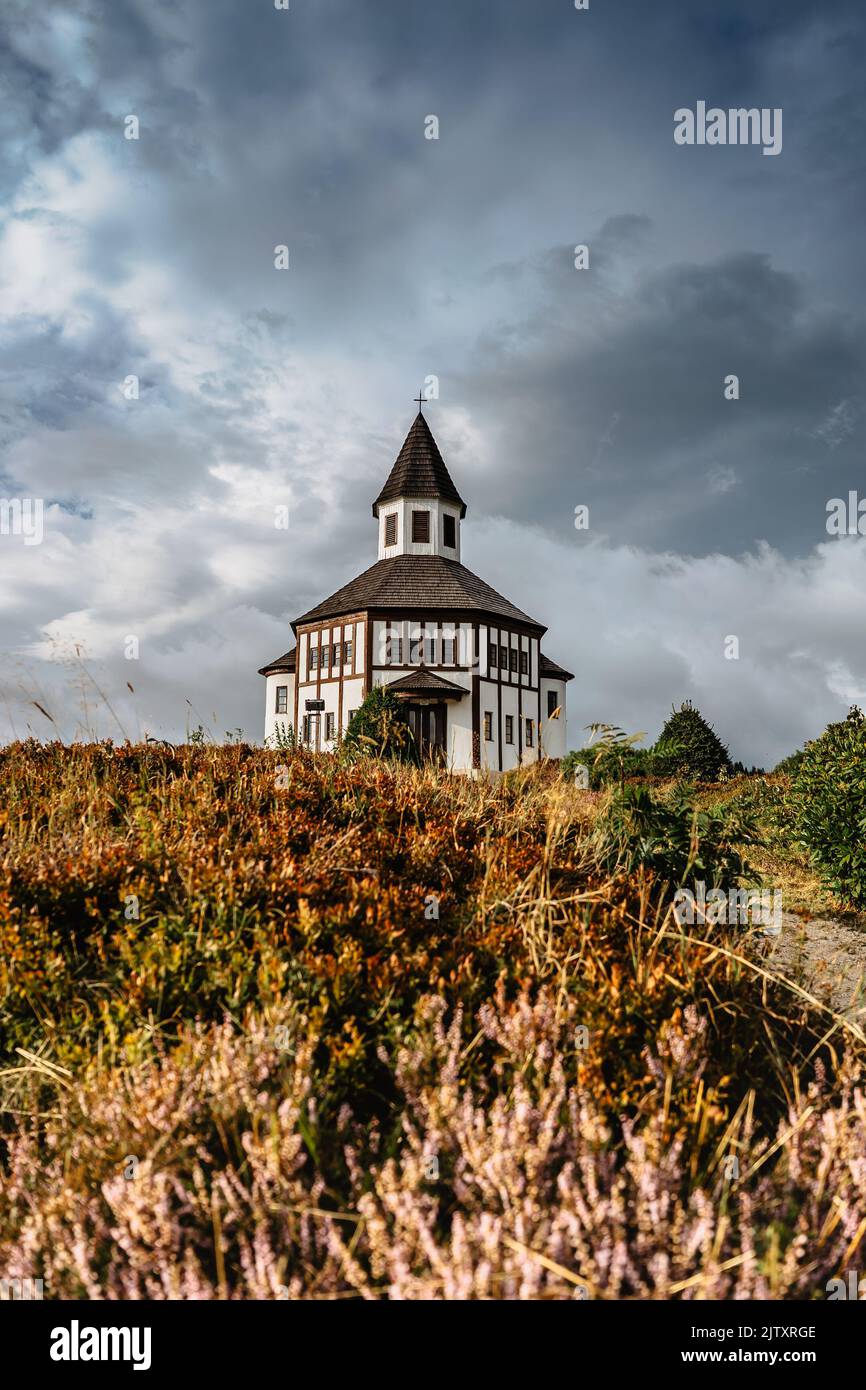 Small white rural Tesarovska chapel with cemetery in village of Korenov, Jizera mountains, Czech Republic. Summer landscape, stormy sky.Wooden Stock Photo