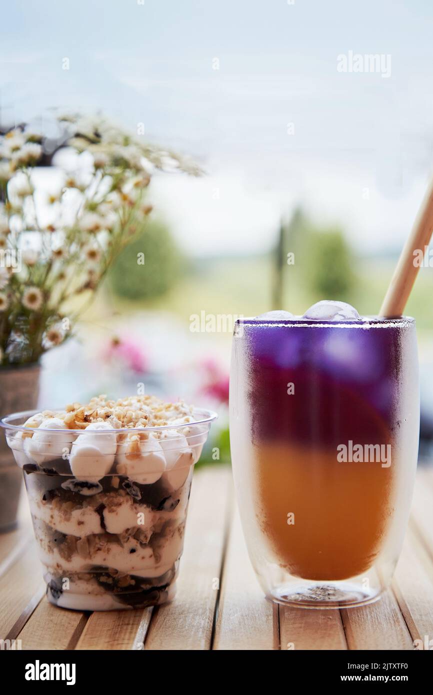 Trendy purple and yellow cocktail with straw reed. Light dessert with ...
