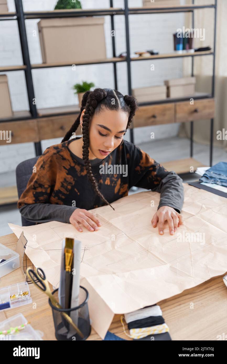 African american designer looking at sewing pattern in workshop,stock image Stock Photo