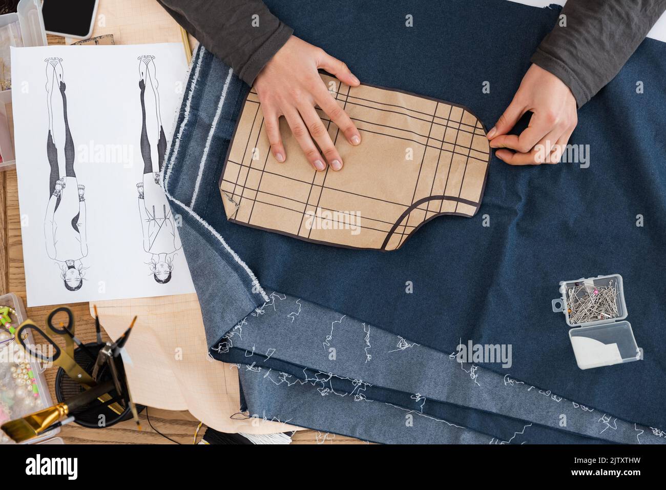 Top view of african american craftswoman holding sewing print near denim cloth and sketch in workshop,stock image Stock Photo