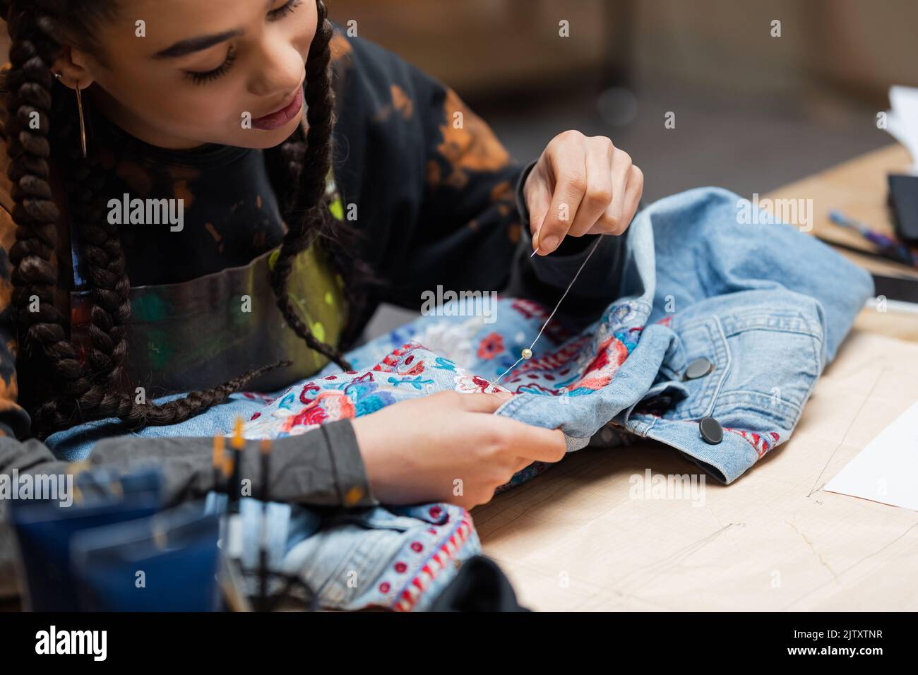 African american designer decorating denim jacket with embroidery in workshop,stock image Stock Photo