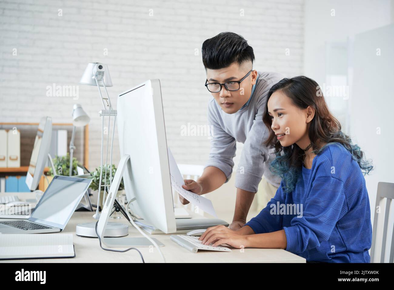 Two colleagues discussing presentation on computer at office Stock Photo