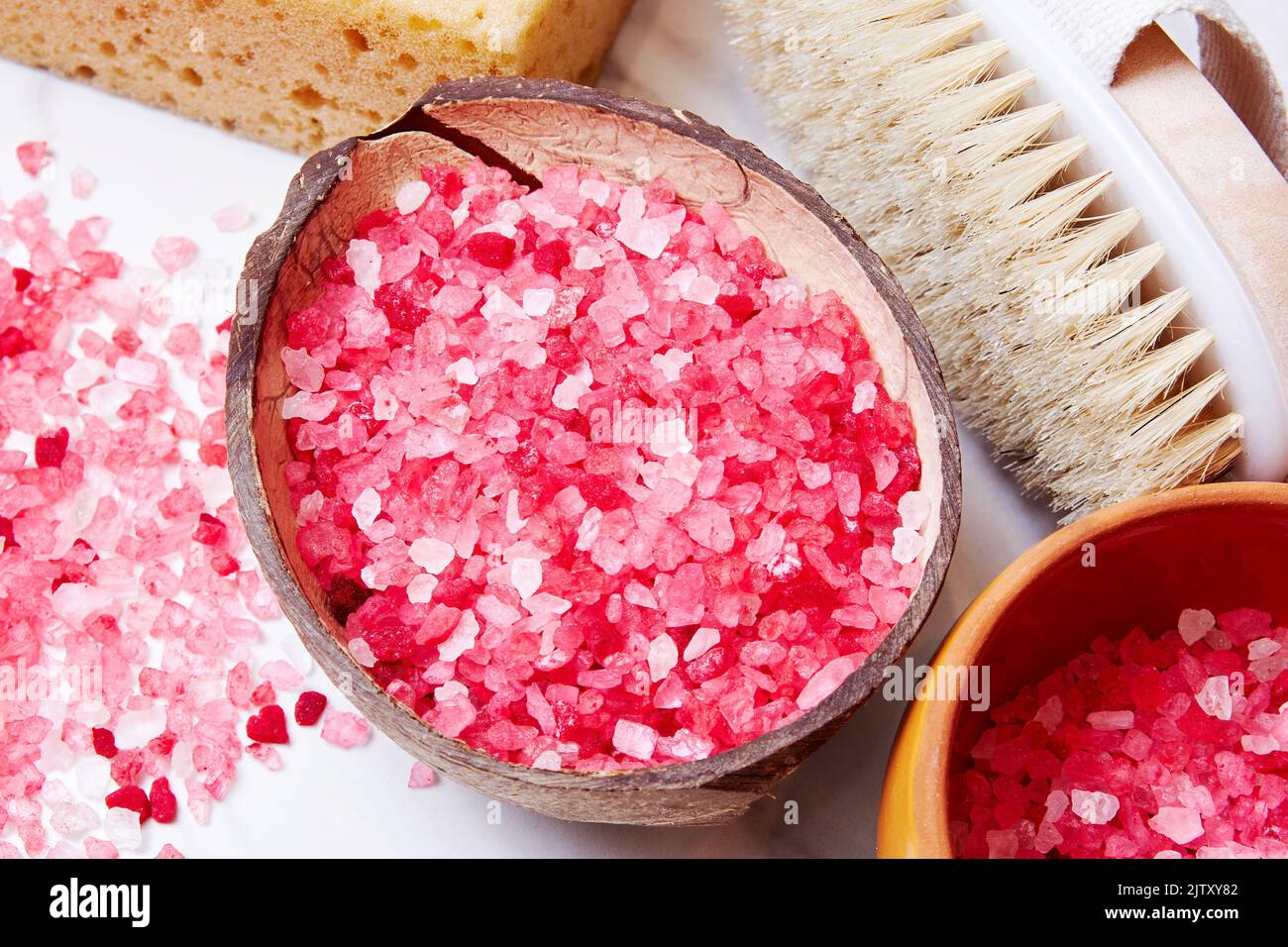 Coconut cup with the pink bath salt grain and wooden brush. Spa