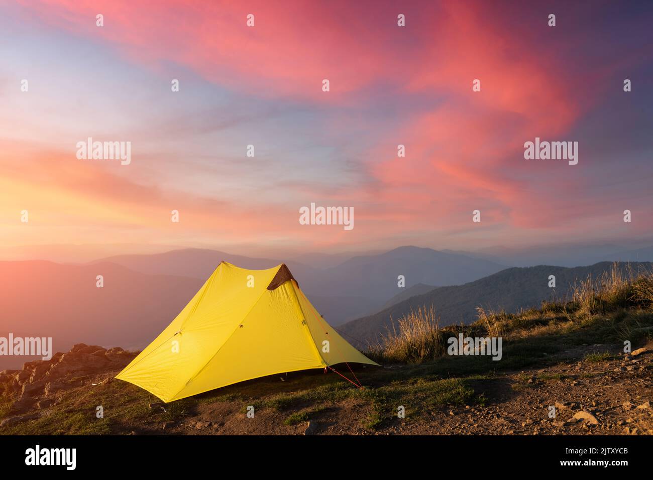 Yellow tent against the backdrop of an incredible mountain landscape during gorgeous sunset. Amazing highland. Tourism concept Stock Photo