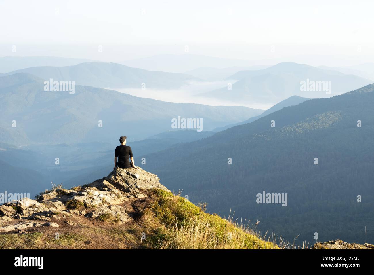 Alone tourist on the edge of the cliff against the backdrop of an incredible sunrise mountains landscape. Travel concept Stock Photo