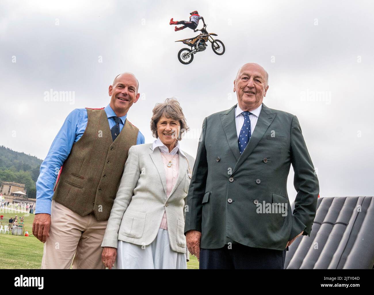 A member of the Bolddog Lings FMX Display Team performs over show president Phil Spencer (left) and the Duke and Duchess of Devonshire during a photocall at the Chatsworth Country Fair in Bakewell, Derbyshire. Picture date: Friday September 2, 2022. Stock Photo