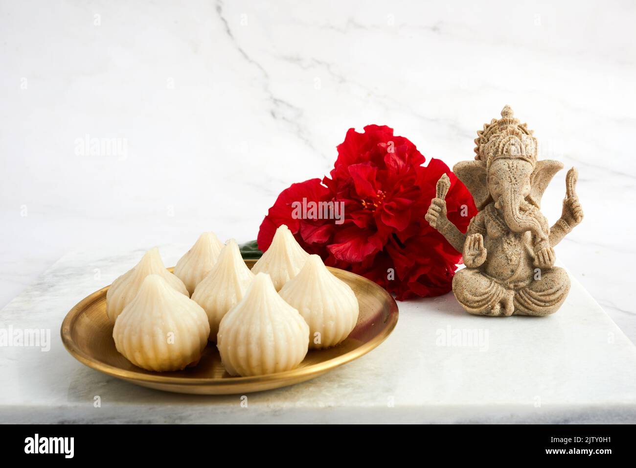 Idol of lord Ganesha with Modak Sweet Dish and flower. Ganesh chaturthi Stock Photo