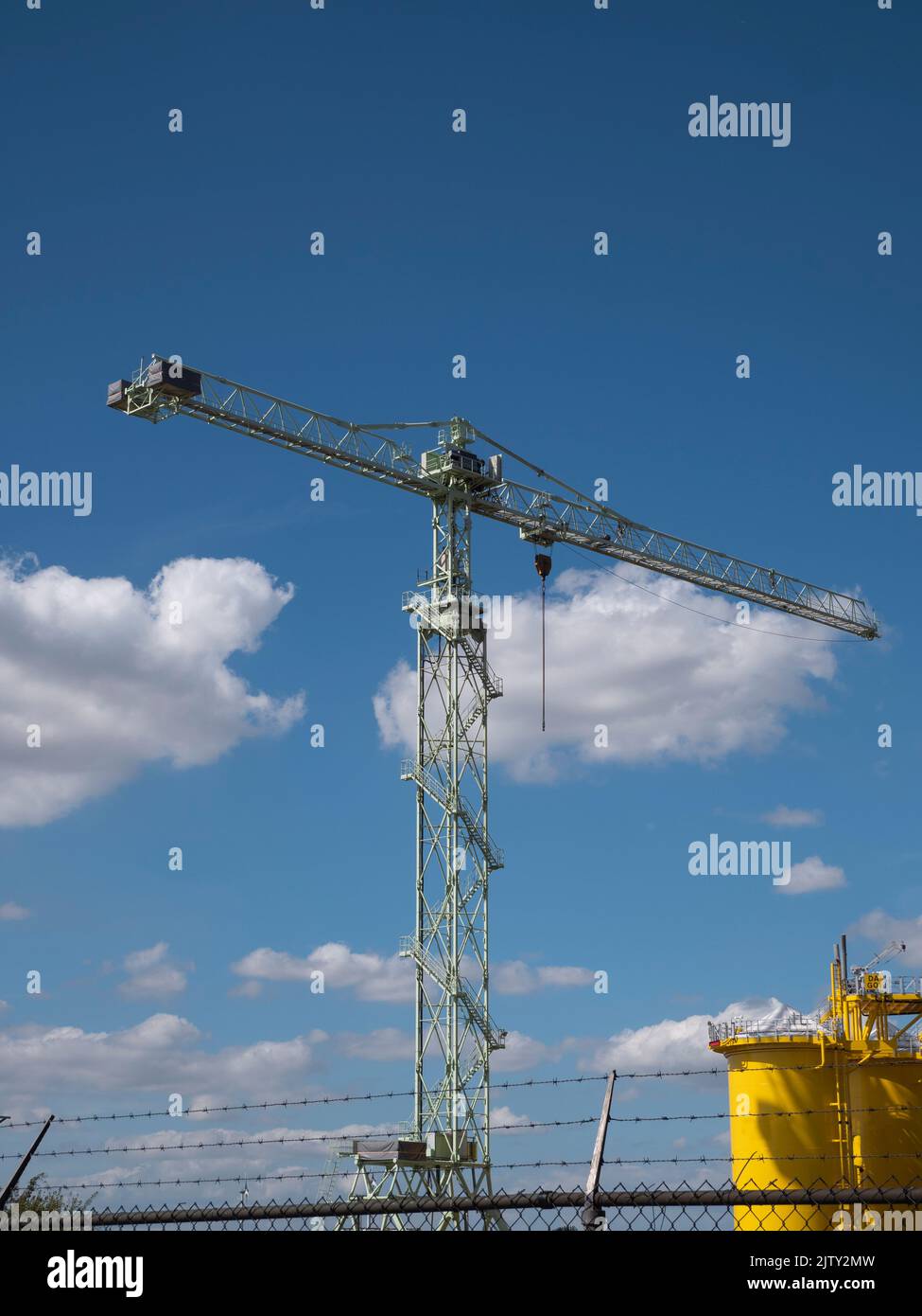 Large industrial crane with iron stairs and a blue cloudy sky Stock Photo