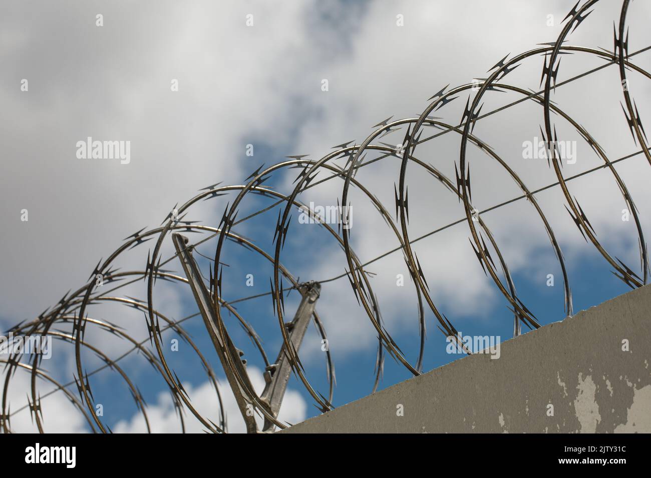 Chain link fence with barbed wire and razor wire. against the blue sky Stock Photo Alamy