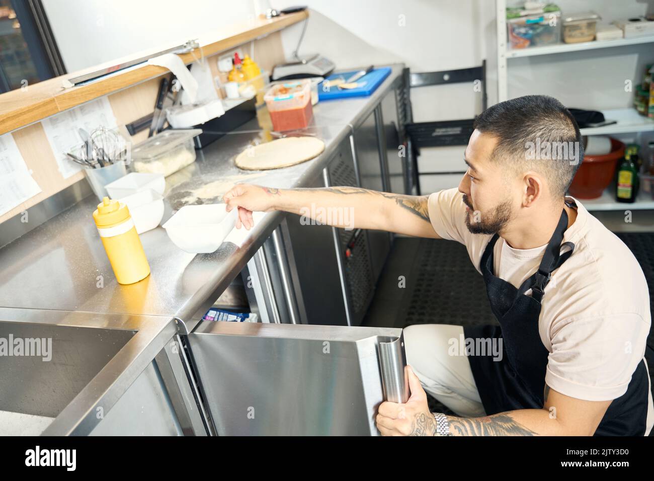Asian guy in apron preparing his kitchen for a cook-off Stock Photo
