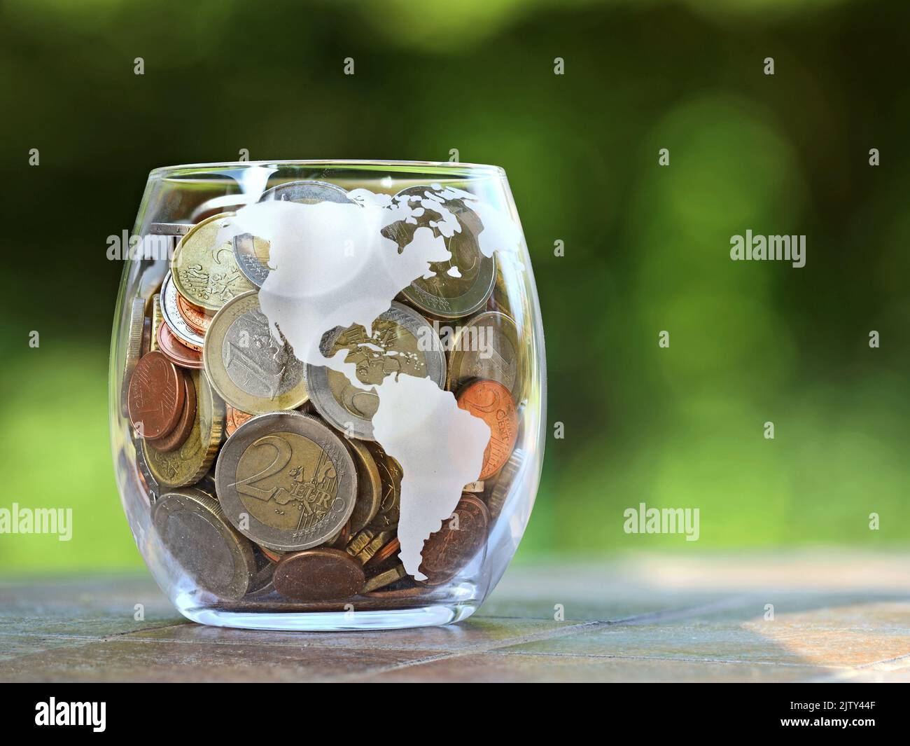 euro coins collected for vacation in glass jar with america map inprint, green blured background Stock Photo