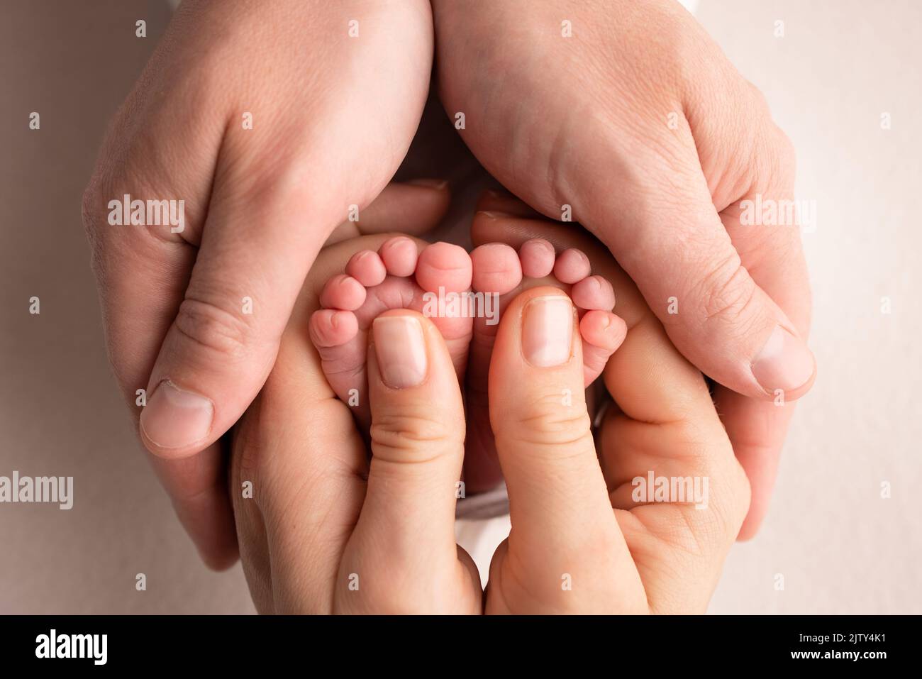 Mother is doing massage on her baby foot. Closeup baby feet in mother hands.  Stock Photo