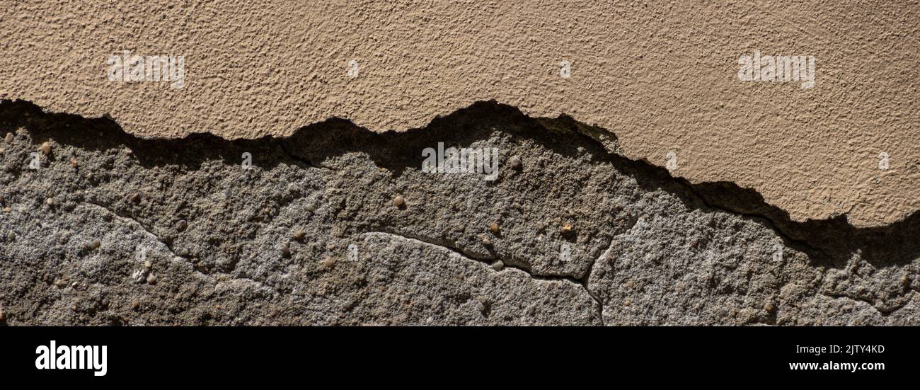 Old sandstone wall with thick pieces of plaster broken off Stock Photo