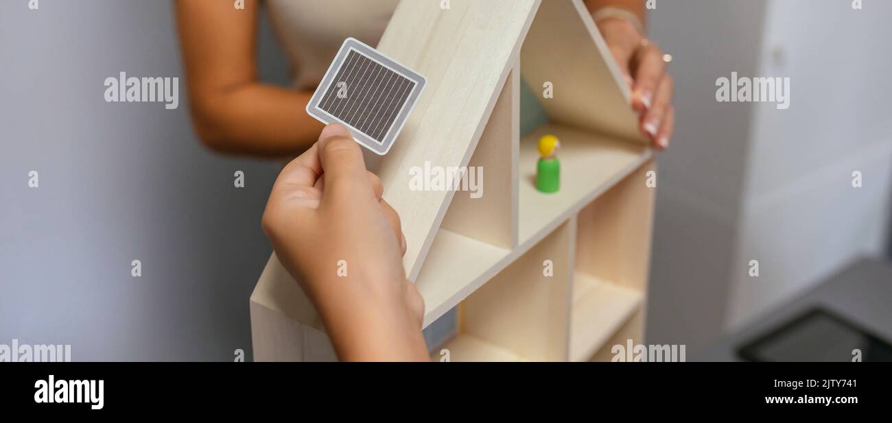 Unrecognizable student placing a solar panel on the roof of a toy house Stock Photo