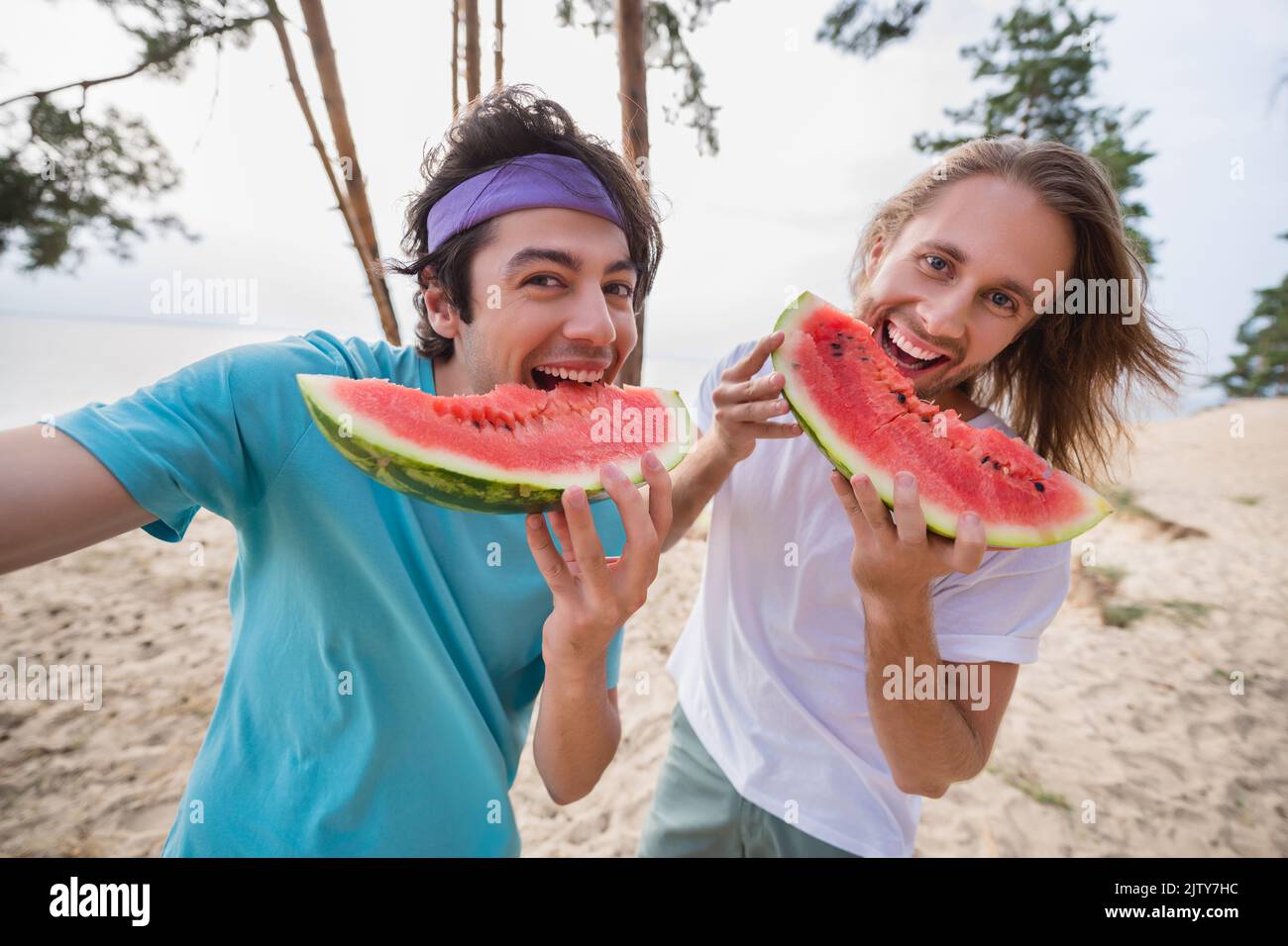 Photo of funky guys eat watermelon do selfie wear casual cloth outside near the river trees Stock Photo