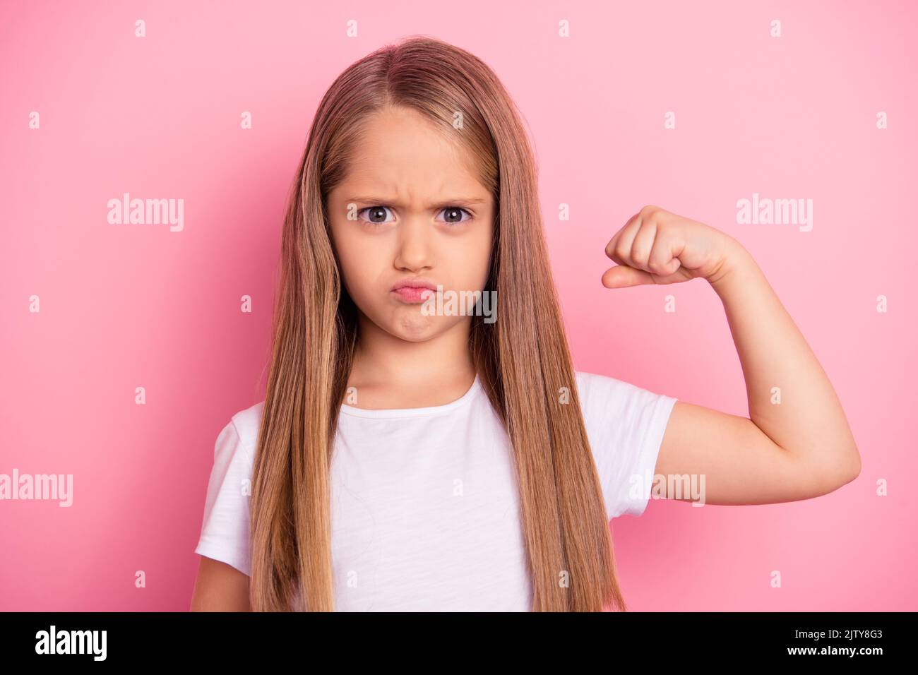 Photo of sportive little girl hand flexing demonstrating biceps isolated on pink color background Stock Photo