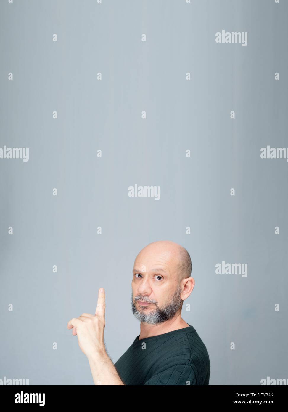 Portrait of mature man standing on white background. Bald bearded man making gestures. Formal style. Stock Photo