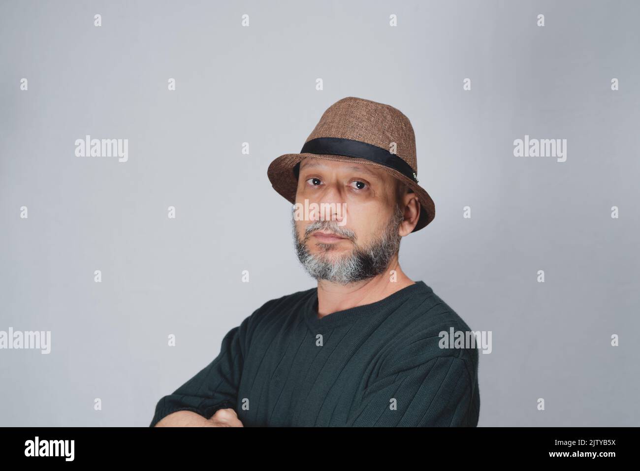 Portrait of mature man standing on white background. Bald bearded man in a brown hat. Formal style. Stock Photo