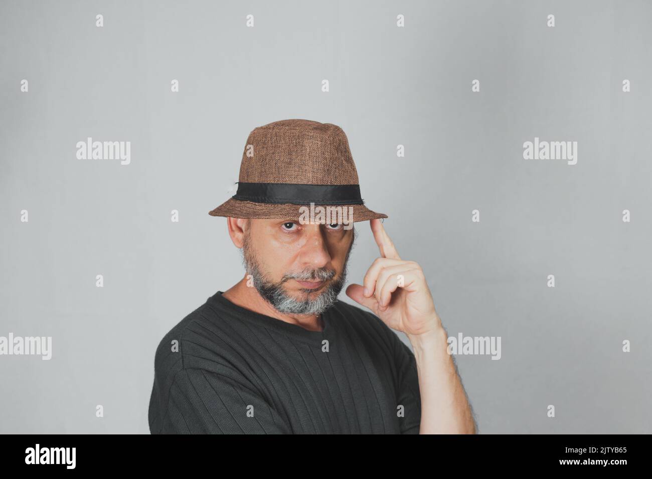 Portrait of mature man standing on white background. Bald bearded man in a brown hat. Formal style. Stock Photo