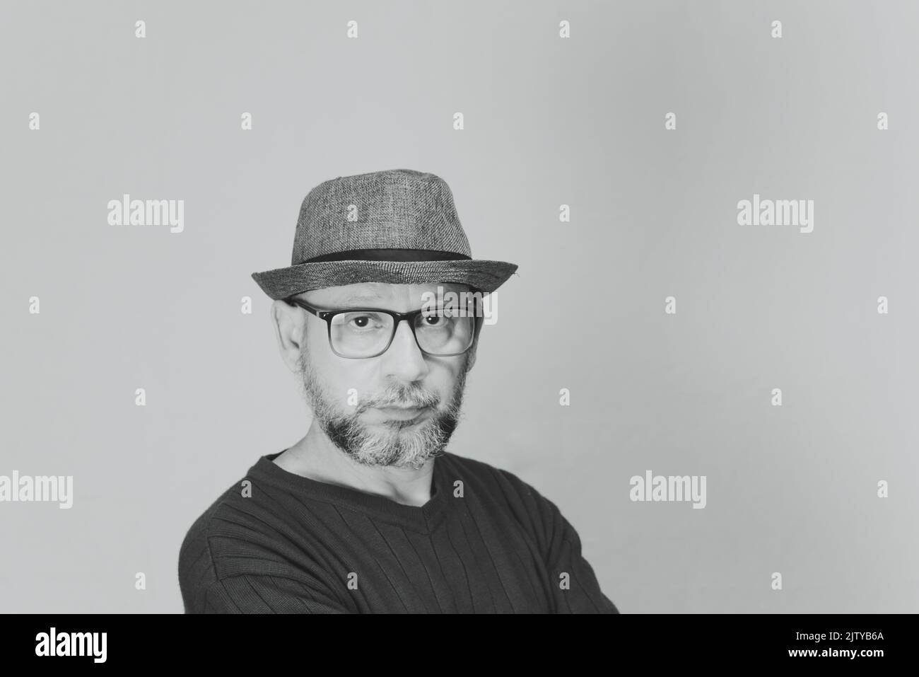 Black and white portrait of mature serious man. Wearing eyeglasses and a hat. Formal style. Stock Photo