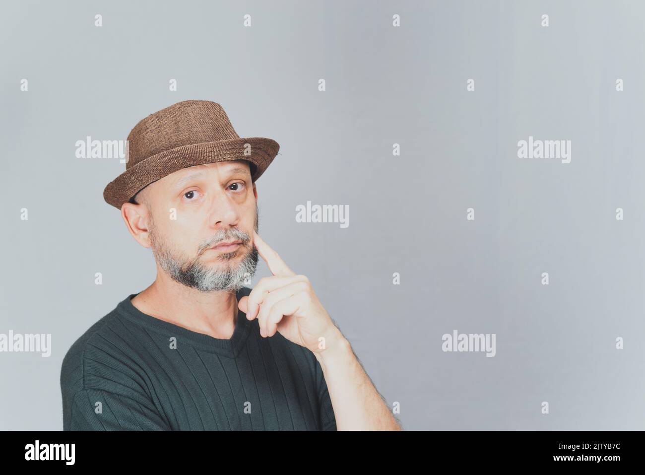 Portrait of mature man standing on white background. Bald bearded man in a brown hat. Formal style. Stock Photo