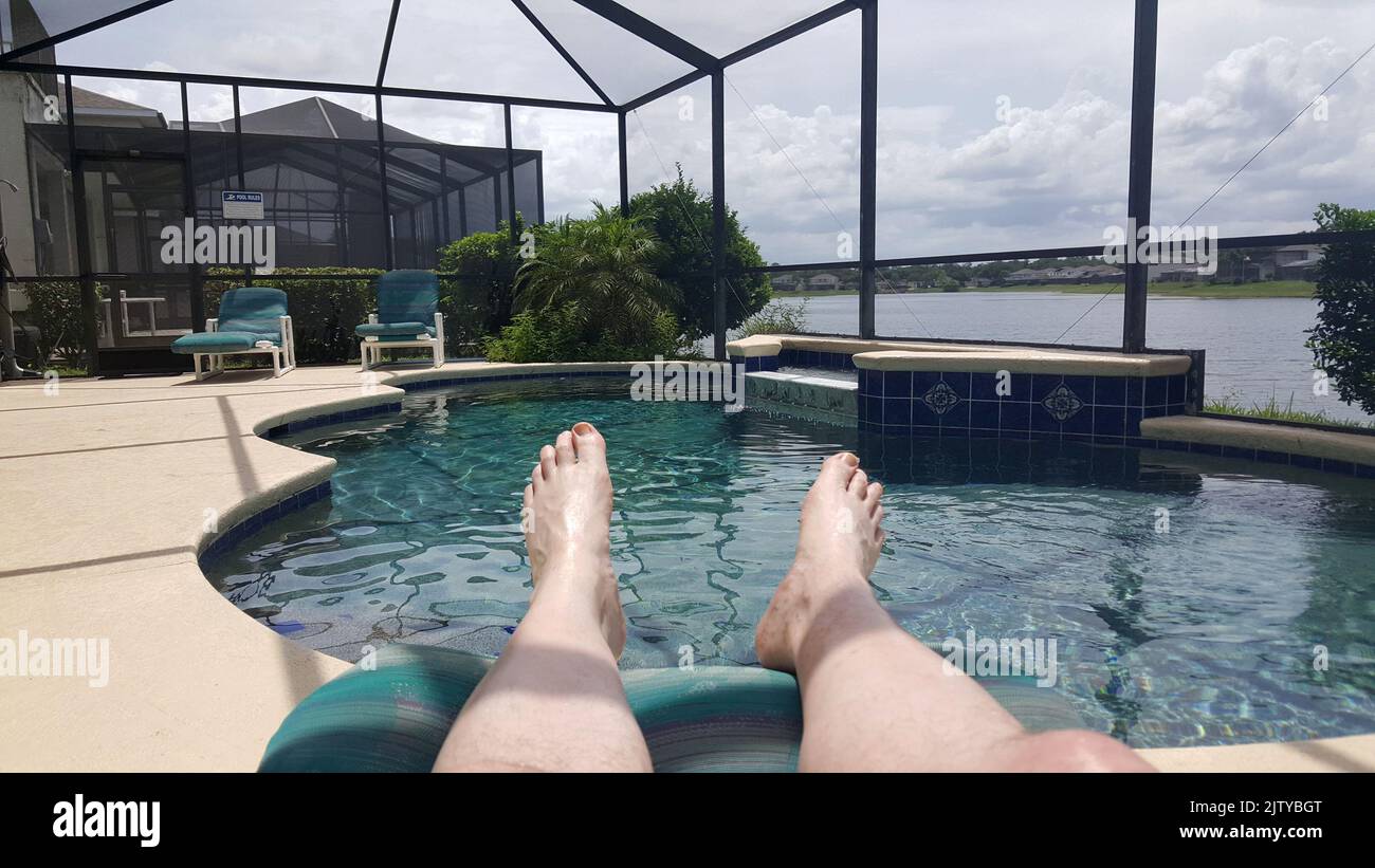 man lying by small pool with inset mesh cage in a villa in a development in kissimmee florida usa Stock Photo