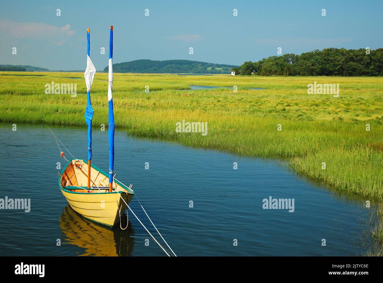 A lone boat sits in a salt marsh on a calm summer day Stock Photo