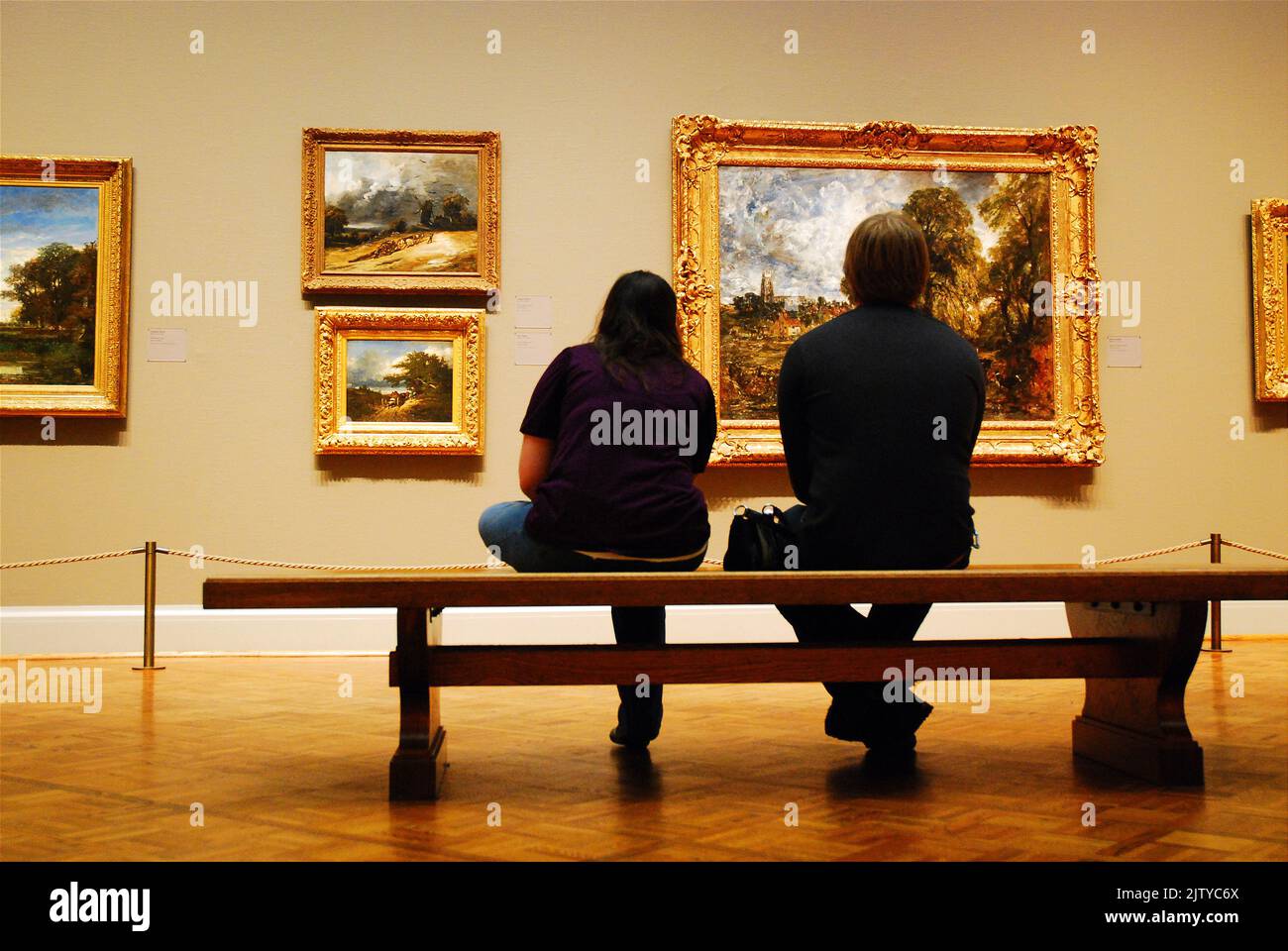 A young adult couple spends a romantic date viewing the European Renaissance master paintings while sitting on a bench in the Art Institute of Chicago Stock Photo
