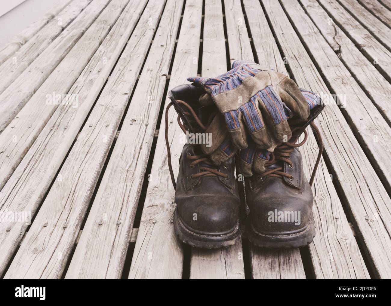 Work boots and gloves on weathered deck boards Stock Photo