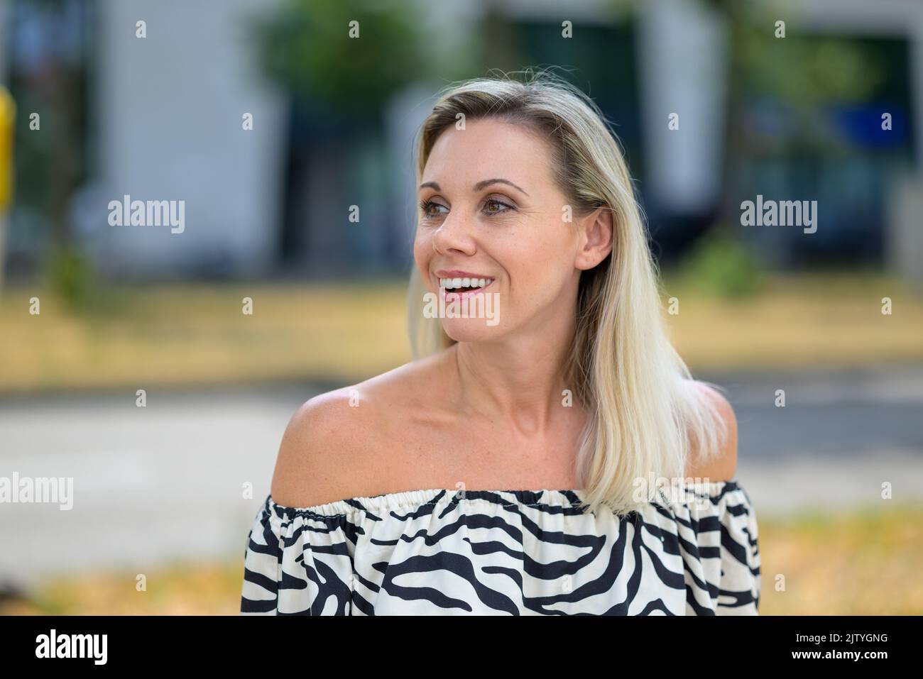 Happy vivacious woman with a lovely warm smile looking round with an expression of delight Stock Photo