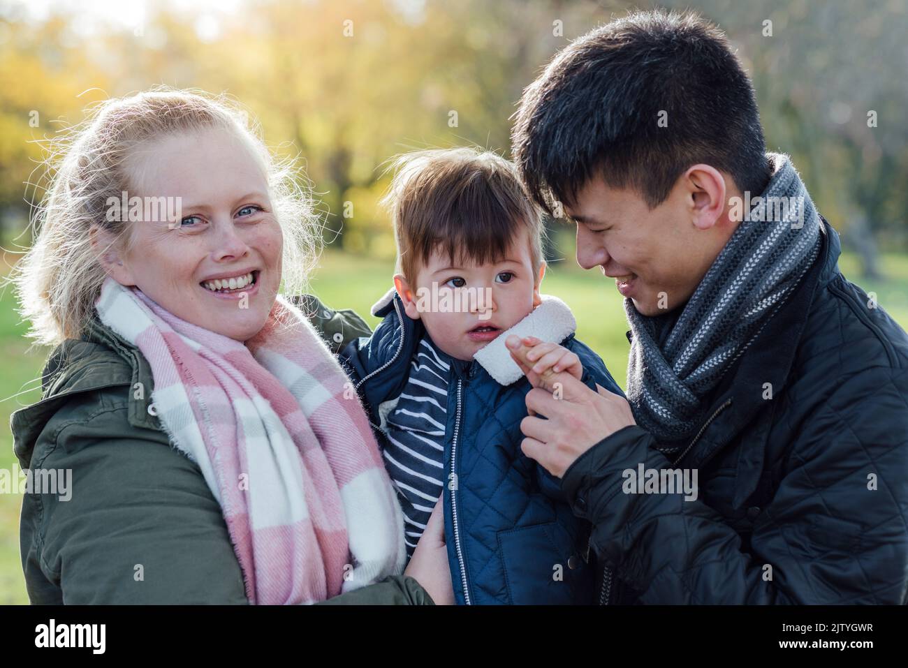 A family standing together outdoors in nature in Northumberland, North East England during Autumn. The woman is holding the baby son while the dad loo Stock Photo