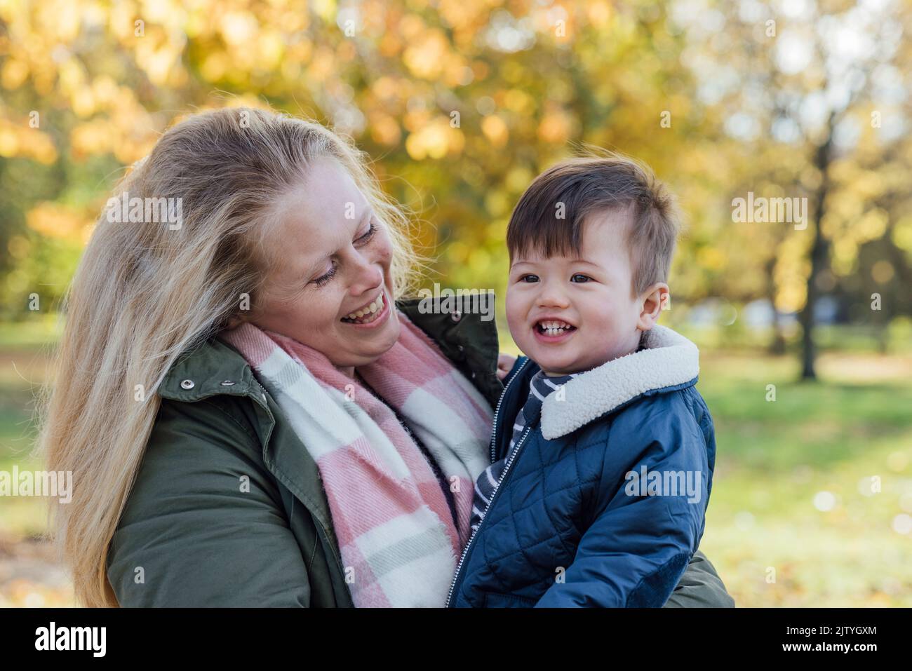A mid adult woman carrying her baby boy in her arms while standing outside and embracing him in nature in Northumberland, North East England. The woma Stock Photo