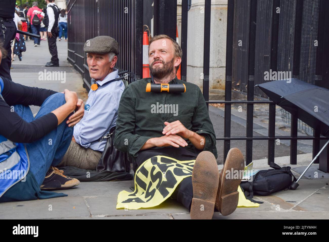 London, UK. 2nd September 2022. Activists sit with necks locked to the fence outside Parliament. Extinction Rebellion protesters glued themselves inside the Parliament while others locked and glued themselves outside, demanding a Citizens' Assembly. Credit: Vuk Valcic/Alamy Live News Stock Photo