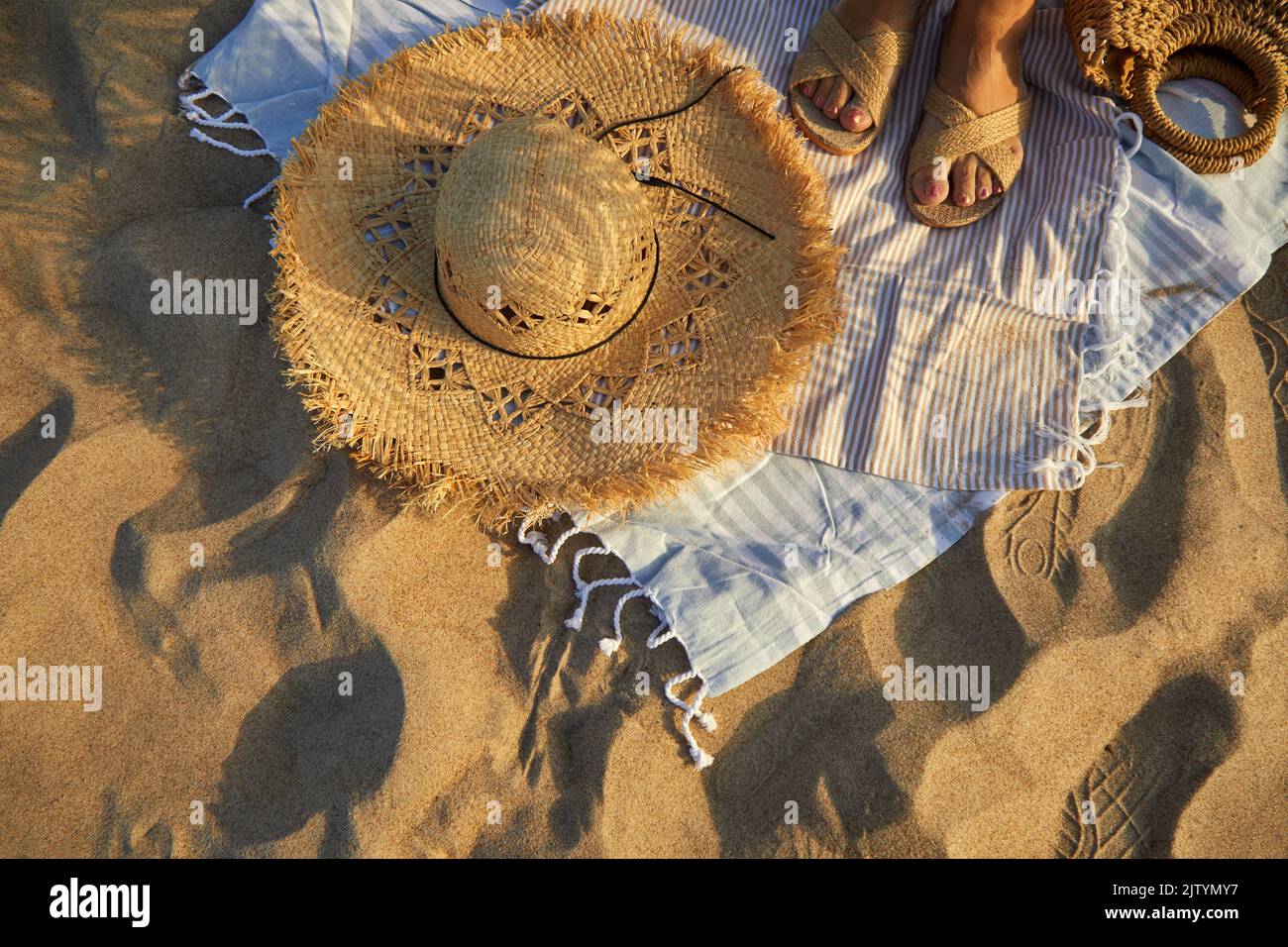 Top view of beach accessories. Straw hat, bag, flip flops on sand at ...
