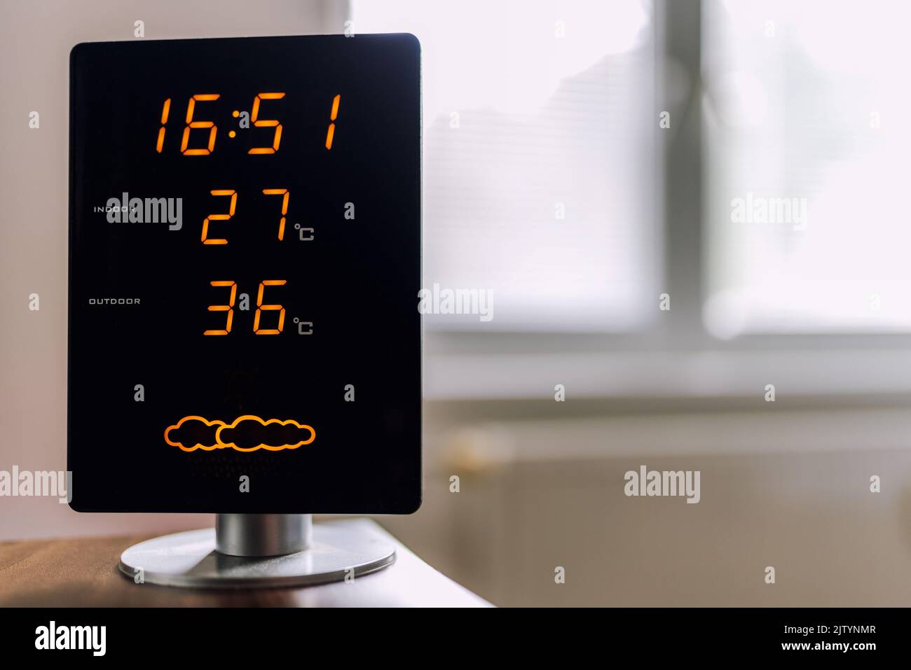 Hot summer day. High temperatures showing on display of home meteo station. Sun shine through window. Stock Photo